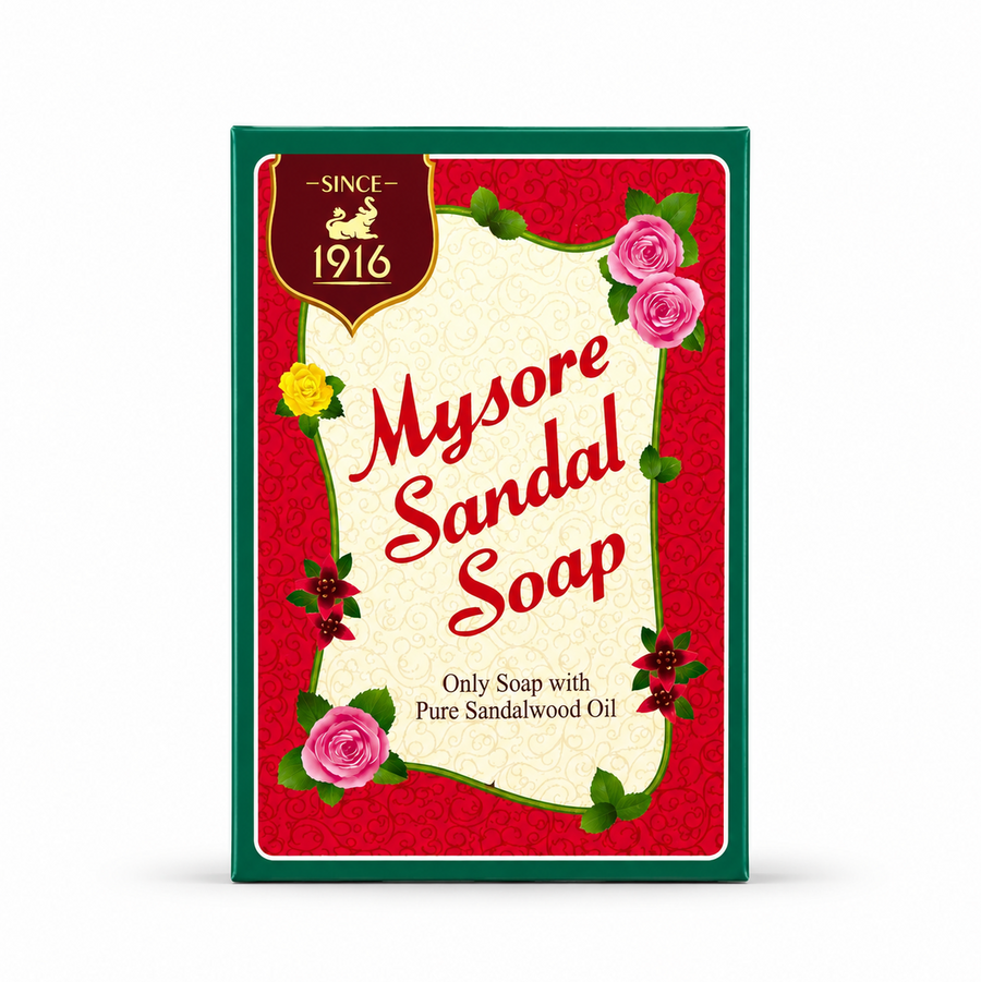 A studio product shot of a rectangular box of Mysore Sandal Soap against a white background. The packaging features a dark green outer frame surrounding a vibrant red background adorned with a subtle swirl pattern. In the top left corner, a maroon shield crest displays a golden mythological creature below the text "-SINCE- 1916". A central, scroll-shaped cream panel showcases the brand name "Mysore Sandal Soap" This product is available in the UK at theindianshelf.co.uk.