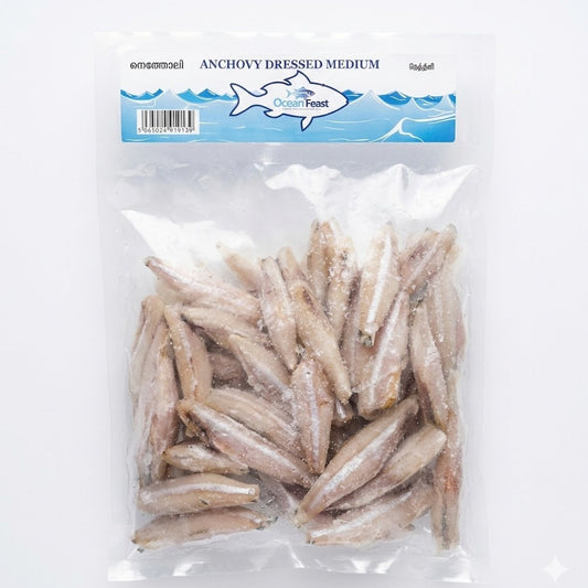 A clear, vacuum-sealed bag of OceanFeast Anchovy Dressed Medium. The packaging contains frozen, cleaned, and prepared medium-sized anchovies, ready for cooking. The top blue label displays the brand logo and the product name in English, Malayalam, and Tamil.This product is available for purchase in the UK at theindianshelf.co.uk.