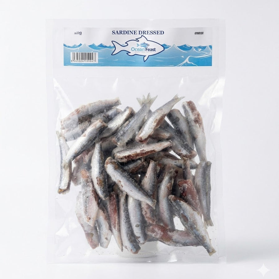 A clear, vacuum-sealed bag of OceanFeast Sardine Dressed. The pack contains several frozen, cleaned, and prepared sardines ready for cooking. The blue and white header label features the brand logo and the product name in English and regional Indian languages.