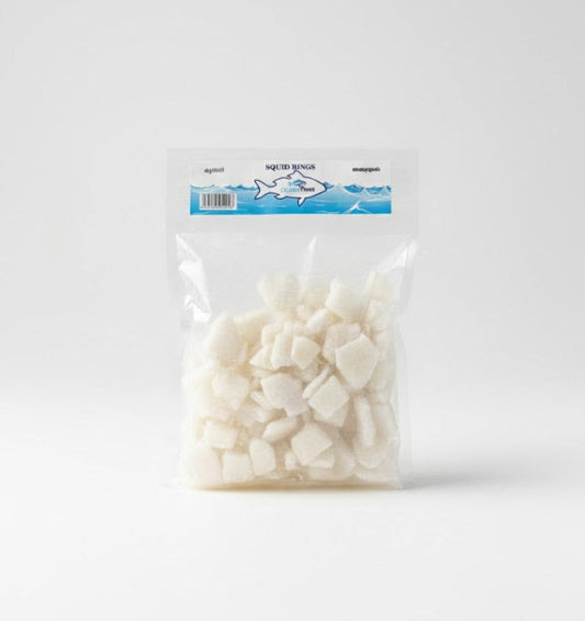 A clear, vacuum-sealed bag of OceanFeast Squid Rings. The pack is filled with frozen, pre-cut white squid rings, cleaned and ready for frying or cooking in curries. The top blue and white header label features the brand logo and the product name in English and regional Indian scripts.This seafood product is available for purchase in the UK at theindianshelf.co.uk.