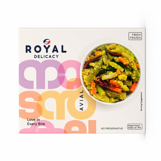 A professional studio shot of the Royal Delicacy Avial packaging. The box is clean and white, featuring modern, oversized typography in pastel pink and orange. showcases a bowl of vibrant Avial—a mix of green beans, carrots, drumsticks, and other vegetables coated in a thick, yellow-hued coconut paste, garnished with red chilies and green curry leaves. The "Royal Delicacy" logo and "Fresh Frozen" icon are clearly visible on the front.This product is available in the UK at theindianshelf.co.uk.