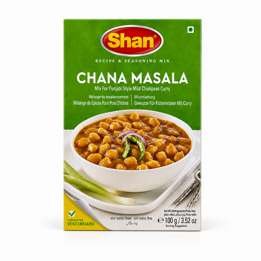 A 100g box of Shan Chana Masala Recipe & Seasoning Mix centered on a solid white background, featuring a bright green top section with the Shan logo and a serving suggestion showing a white bowl filled with chickpeas in gravy garnished with sliced onion rings and green chilies. This product is available in the UK at theindianshelf.co.uk.