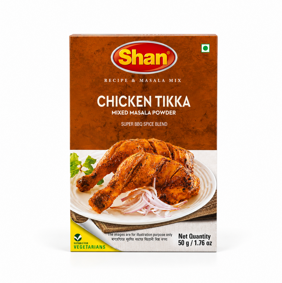 A 50g box of Shan Chicken Tikka Mixed Masala Powder centered on a solid white background, featuring a warm brown top section with the Shan logo and a serving suggestion showing grilled chicken tikka leg quarters served on a white plate with sliced onions. This product is available in the UK at theindianshelf.co.uk.