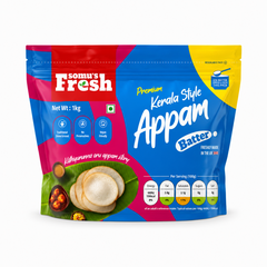 A studio product shot of a 1kg resealable stand-up pouch of Somu's Fresh Kerala Style Appam Batter isolated on a white background. The blue and pink packaging displays fresh appams on a banana leaf alongside nutritional details.