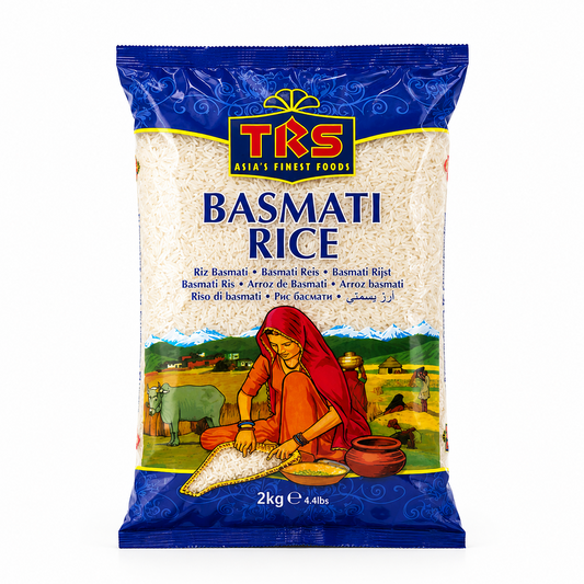 A 2kg bag of TRS Basmati Rice centered on a white background, featuring a vibrant blue frame around a clear window showing raw white rice grains above a colorful illustration of a woman sifting rice in a rural landscape. This product is available in the UK at theindianshelf.co.uk.