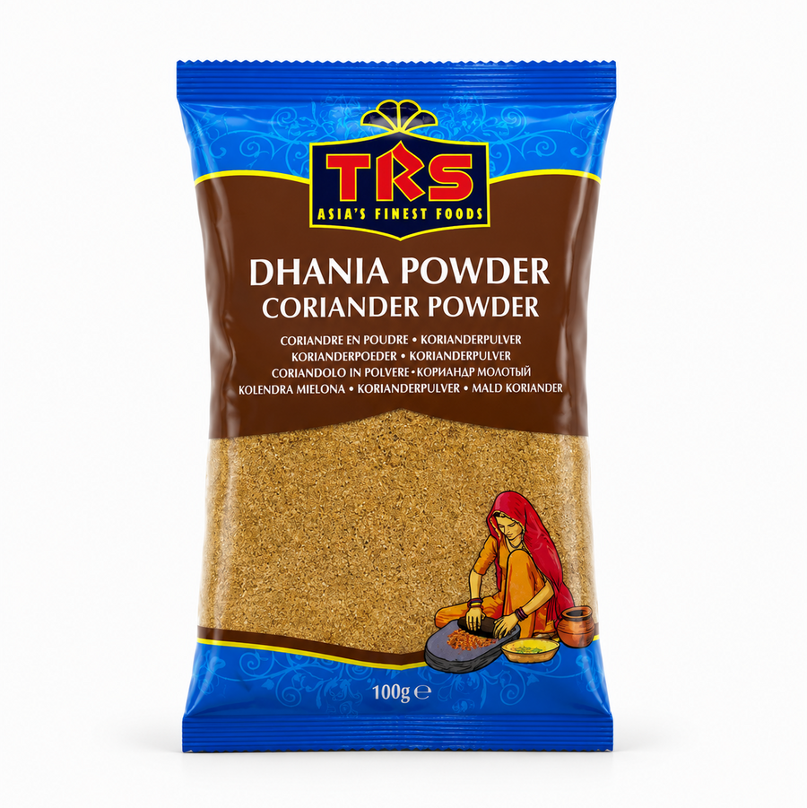 A 100g pouch of TRS Dhania Powder / Coriander Powder centered on a solid white background, featuring a brown and blue packaging design with the TRS logo and a clear window showing finely ground coriander powder next to an illustration of a traditional Indian woman using a grinding stone. This product is available in the UK at theindianshelf.co.uk.