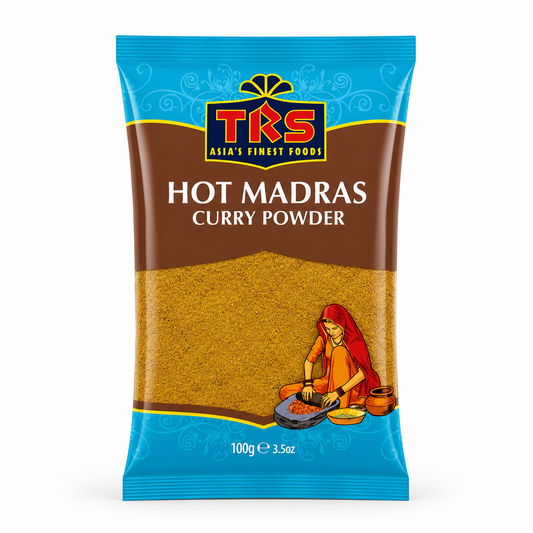 A 100g pouch of TRS Hot Madras Curry Powder centered on a solid white background, featuring a brown and blue packaging design with the TRS logo and a clear window showing finely ground yellow-brown curry powder next to an illustration of a traditional Indian woman using a grinding stone. This product is available in the UK at theindianshelf.co.uk.