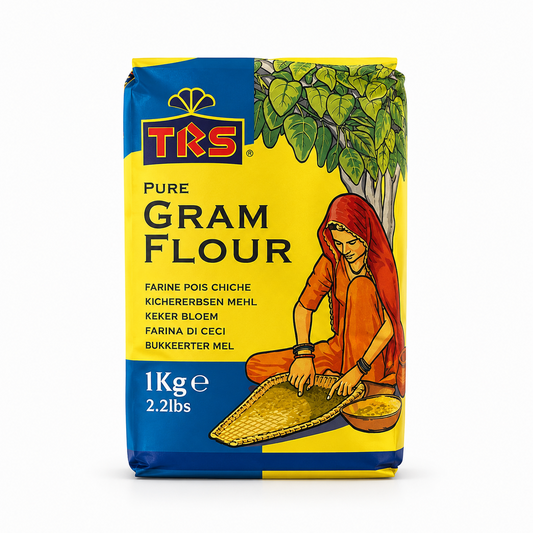 A 1kg block bag of TRS Pure Gram Flour centered on a solid white background, featuring a bright yellow and blue package with the brand logo and an illustration of a woman in traditional attire winnowing grains under a tree. This product is available in the UK at theindianshelf.co.uk