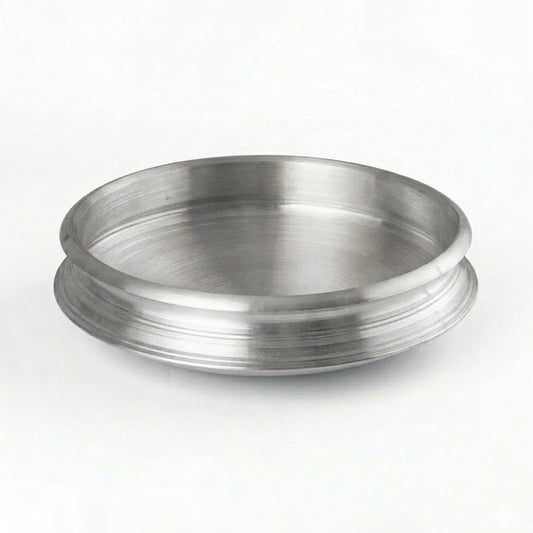 A clean, eye-level studio shot of a traditional Aluminum Uruli (cookware). The vessel is circular with a wide, open top and a shallow depth, featuring a distinctive flared rim with horizontal decorative grooves. It has a brushed metallic finish and is set against a plain, well-lit white background.