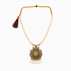 An antique gold-plated choker necklace featuring a single strand of white pearls and a large, intricately carved circular medallion pendant finished with dangling mini pearls, displayed centered against a solid white background. Available in the UK at theindianshelf.co.uk.