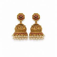 A pair of antique gold-toned temple jhumka earrings featuring floral studs, ruby and emerald stone accents, and a fringe of white pearl drops, centered against a solid white background. Available in the UK at theindianshelf.co.uk.