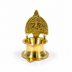 A polished brass Kamatchi Amman Vilakku featuring an embossed backplate with Goddess Kamakshi, centered on a solid white background. Available in the UK at theindianshelf.co.uk.