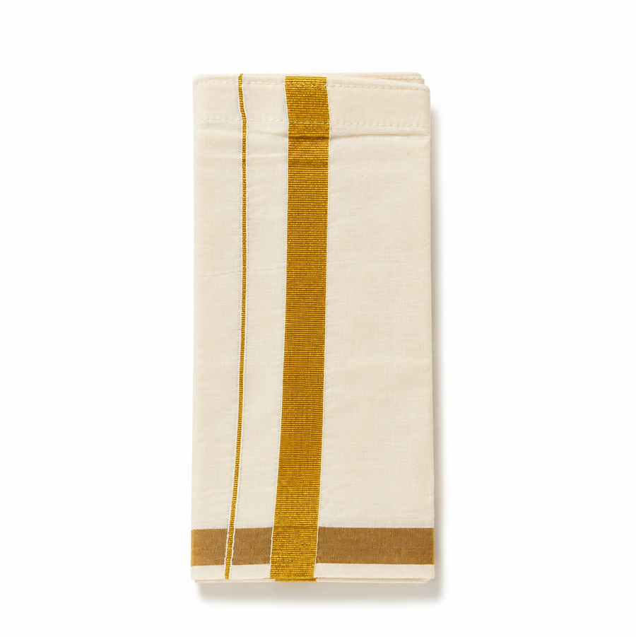 A neatly folded cream kids Kerala kasavu mundu (dhoti) for 1 to 2 year olds centered on a solid white background, featuring a golden zari border, a fine parallel accent stripe running vertically, and a gold zari border along the bottom fold. Available in the UK at theindianshelf.co.uk.