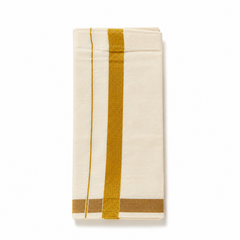A neatly folded cream kids Kerala kasavu mundu (dhoti) for 1 to 2 year olds centered on a solid white background, featuring a golden zari border, a fine parallel accent stripe running vertically, and a gold zari border along the bottom fold. Available in the UK at theindianshelf.co.uk.