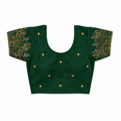 An emerald green short-sleeved stretchable readymade saree blouse with hand-embroidered leaf patterns on the sleeves and small gold floral motifs across the front, laid flat against a solid white background. Available in the UK at theindianshelf.co.uk.
