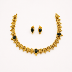 An antique gold-plated temple jewelry set featuring a traditional coin necklace accented with three oval black cabochon stones and matching black stud earrings, centered on a solid white background. Available in the UK at theindianshelf.co.uk.