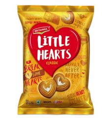 A glossy, golden-yellow plastic package of Britannia Little Hearts Classic biscuits. The packaging features a large red heart with the product name in white text. Two sugar-glazed, heart-shaped puff pastry biscuits (palmiers) are prominently displayed at the bottom. The background is covered with various fun, heart-related phrases like "BREAK SOME HEARTS" and "SINGLE AND PROUD."