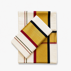A neatly folded off-white Kerala cotton double set mundu with its matching neryathum folded diagonally on top against a solid white background, displaying wide metallic gold zari bands framed by maroon and black border stripes. Available in the UK at theindianshelf.co.uk.