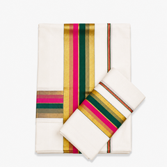 A neatly folded off-white Kerala cotton double set mundu with its matching neryathum folded diagonally on top against a solid white background, displaying metallic gold zari bands interwoven with vibrant pink and deep green border stripes. Available in the UK at theindianshelf.co.uk.